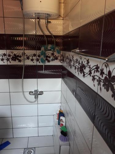 een badkamer met een douche met zwarte en witte tegels bij City Apartment in Visoko