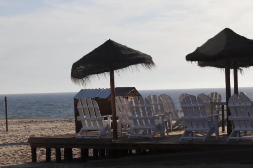 a group of chairs and umbrellas on a beach at Monte do Parral in Santiago do Cacém