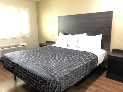 a hotel room with a large bed with white pillows at Simply Home Inn & Suites - Riverside in Riverside