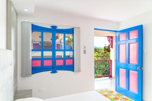a bedroom with a blue and red door and a balcony at Hotel El Jardin in Salento
