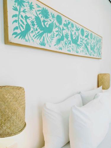 a picture hanging above a bed with white pillows at Hotel Mamá Carlota in Querétaro