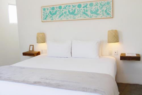 a bedroom with a white bed with two lamps at Hotel Mamá Carlota in Querétaro