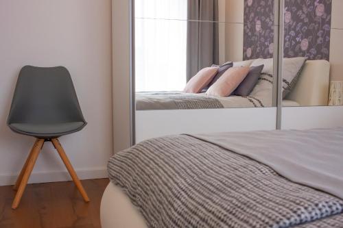 a mirror in a bedroom with a chair and a bed at Center Rev Apartment in Győr