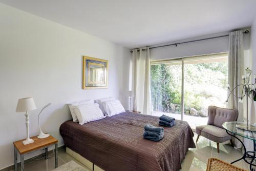 a bedroom with a bed and a large window at Appartement - villa Le Saint Georges avec superbe jardin et vue mer panoramique in Cannes
