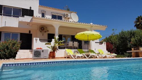 a house with a swimming pool with chairs and an umbrella at Villa Navita in Loulé