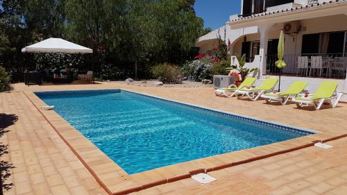 a swimming pool with chairs and a house at Villa Navita in Loulé