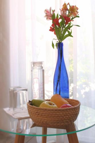 a glass table with a bowl of fruit and a blue vase at Hotel Mamá Carlota in Querétaro