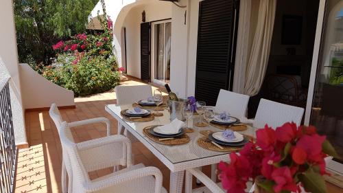 a white table and chairs on a patio with flowers at Villa Navita in Loulé