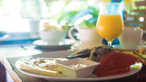 a plate of breakfast food and a glass of orange juice at Hotel El Pequeño Gecko Verde in Sámara