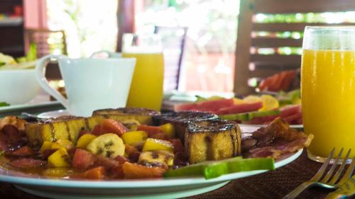 a plate of food on a table next to a glass of orange juice at Hotel El Pequeño Gecko Verde in Sámara