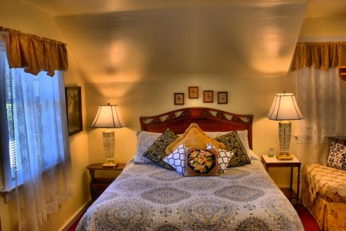 a bedroom with a bed with two lamps and two windows at Bard's Inn in Cedar City