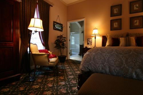 a bedroom with a bed and a chair and a lamp at Yosemite Rose Bed and Breakfast in Groveland