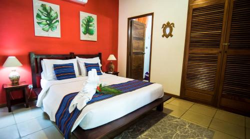 a bedroom with a large bed with red walls at Hotel El Pequeño Gecko Verde in Sámara