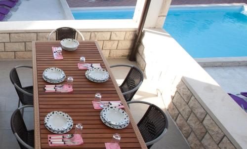 a table with chairs and plates on it next to a pool at Villa Marijeta Hvar in Hvar