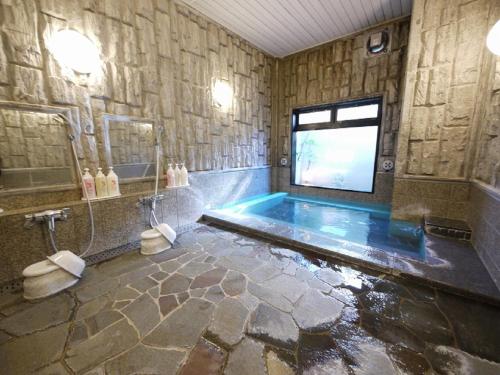 Hotel Route-Inn Shimada Ekimae في Shimada: حمام مع حوض استحمام مع تلفزيون