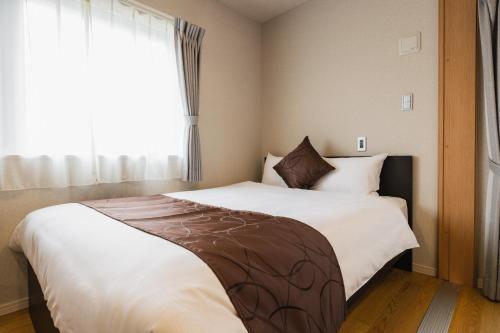 1 dormitorio con 1 cama blanca grande y ventana en Cocolie BEPPU, en Beppu