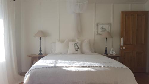 a bedroom with a large white bed with two lamps at Gibbston Boathouse with Outdoor Bath in Gibbston