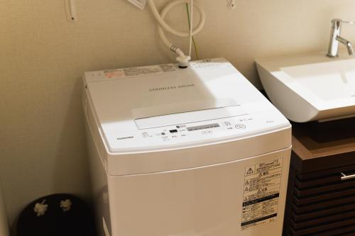 a white washer and dryer sitting next to a sink at Cocolie BEPPU in Beppu