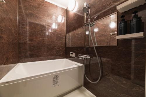 a bathroom with a bath tub and a shower at Cocolie BEPPU in Beppu