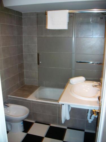 a bathroom with a sink and a tub and a toilet at Hotel Neguri in Getxo