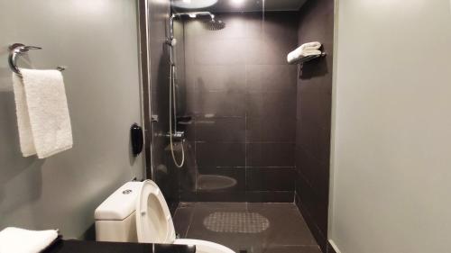 a bathroom with a shower with a toilet and a sink at Amelie Hotel Manila in Manila