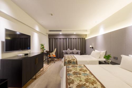 a hotel room with two beds and a flat screen tv at Dashen Hotel Shunde Lecong in Shunde