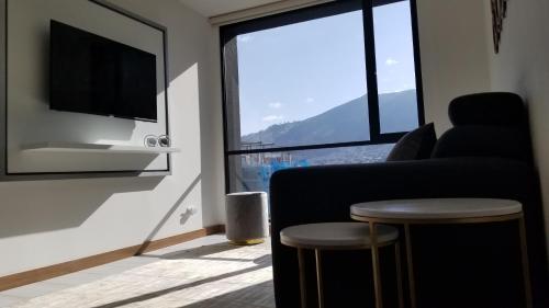 キトにあるLuxury Residence Suitesのリビングルーム(ソファ、テレビ、スツール付)