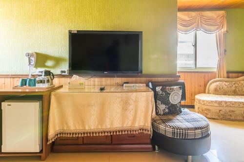 a living room with a tv and a chair at Kenting Maya-House B&B in Kenting