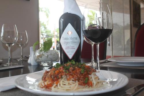 a plate of pasta and a bottle of wine on a table at Chau Pho Hotel in Chau Doc