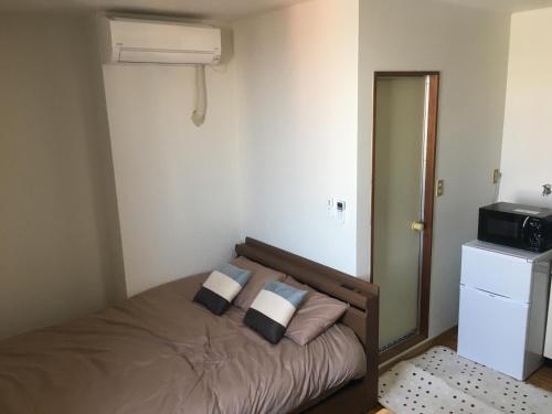 sypialnia z łóżkiem z poduszkami i kuchenką mikrofalową w obiekcie コンドミニアムホテル Stay inn Blue 301号室 w mieście Hukue