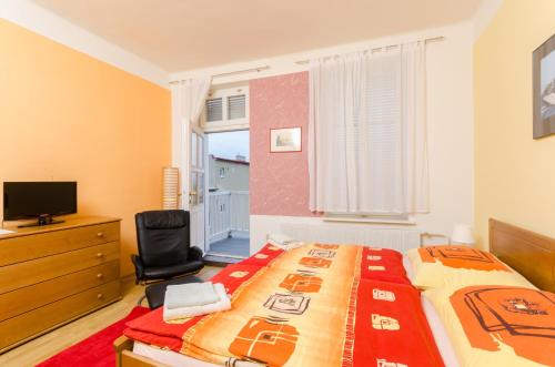 a bedroom with a bed and a chair and a television at Pension Ibérica in Brno