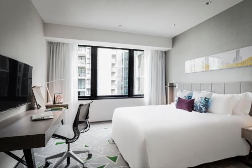 a hotel room with a large bed and a television at Capri by Fraser Brisbane in Brisbane