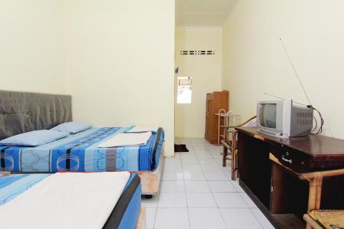 a room with two beds and a television on a desk at Hotel Wijaya 2 Kaliurang in Yogyakarta