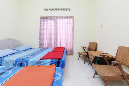 a bedroom with two beds and chairs and a table at Hotel Wijaya 2 Kaliurang in Yogyakarta