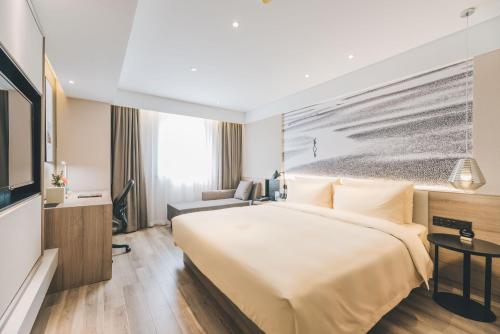 ChangshuにあるAtour Hotel Changshu Changjiang Road Branchの大型ベッド1台、テレビが備わる客室です。