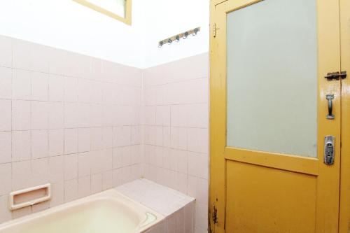 a bathroom with a tub and a yellow door at Hotel Wijaya 2 Kaliurang in Yogyakarta