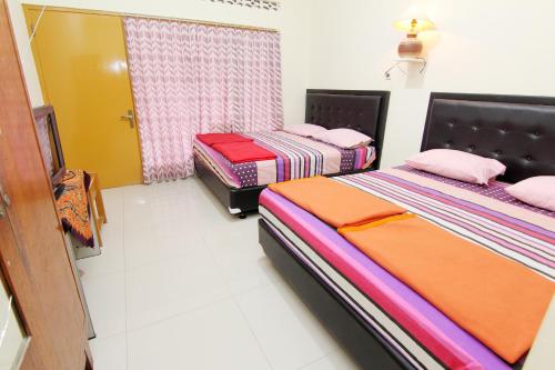 a bedroom with two beds and a window at Hotel Wijaya 2 Kaliurang in Yogyakarta