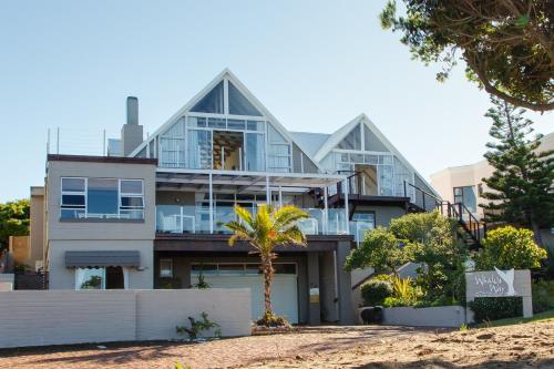 a house with a palm tree in front of it at Whales Way Ocean Retreat in Wilderness