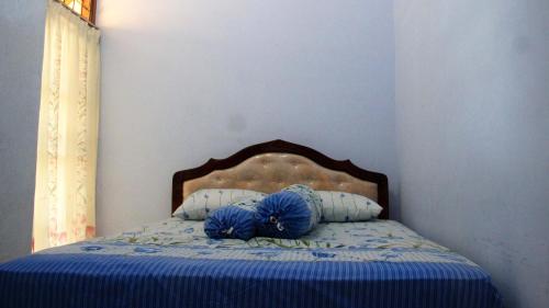 a bed with a blue comforter and two pillows at Menjangan Bali Homestay in Banyuwedang
