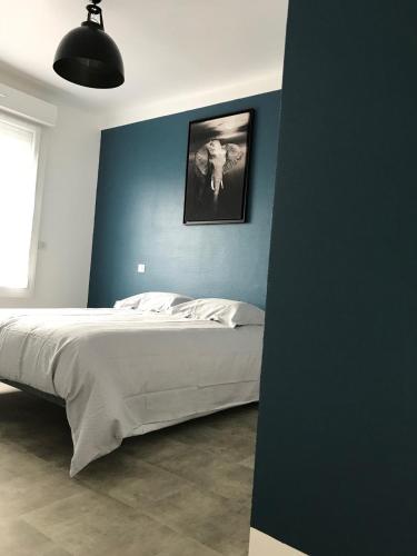 une chambre avec un lit avec un mur bleu dans l'établissement COSMAO - Grand 2 pièces moderne & cosy proche de la gare et du centre, à Lorient