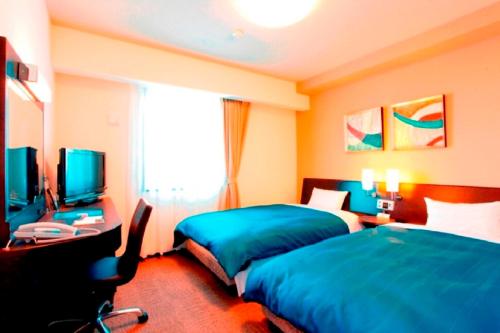 um quarto de hotel com duas camas e uma televisão em Hotel Route-Inn Tsuruoka Ekimae em Tsuruoka