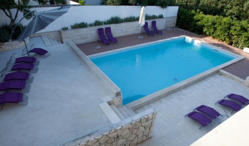 a swimming pool with purple lounge chairs next to it at Villa Marijeta Hvar in Hvar