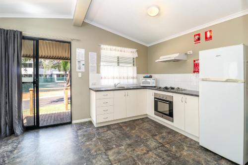 a kitchen with white cabinets and a refrigerator at Discovery Parks - Busselton in Busselton