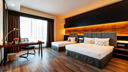 a hotel room with two beds and a desk at Hotel Armada Petaling Jaya in Petaling Jaya