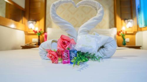 a bouquet of roses and bunny ears on a bed at โรงแรมศิริโฮเต็ล Sirihotel Korat in Nakhon Ratchasima