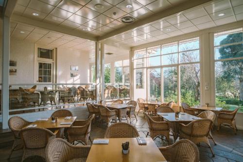 un restaurante con mesas, sillas y ventanas en Chateau Yering en Yarra Glen