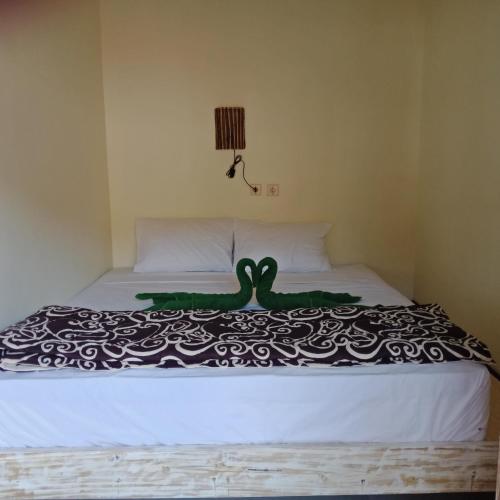 a bedroom with a bed with a green swan on it at Backpackers Home Amed in Amed