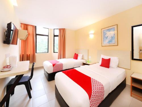a hotel room with two beds and a desk at Super OYO 635 Seven Days Hotel in Raub