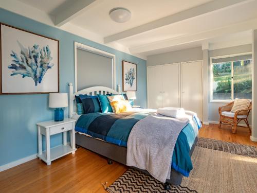 Schlafzimmer mit blauen Wänden, einem Bett und einem Stuhl in der Unterkunft Sea180 Merimbula in Merimbula