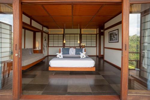 a bedroom with a bed and a porch at Suarapura Resort & Spa in Tegalalang